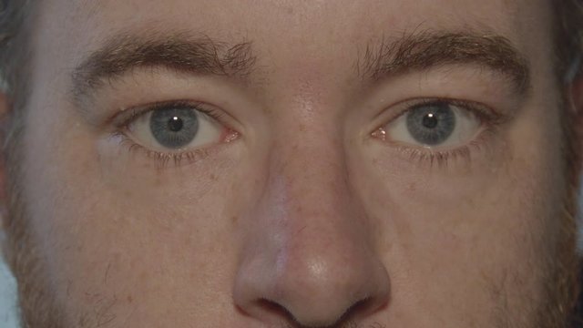 Close up of glasses being removed from pair of blue eyes looking into camera