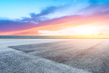 Race track road and lake with colorful clouds at sunset.