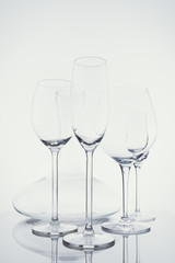 Glassware selection with wine, champagne, liquour glasses and decanter on the light background.. Fine cristal glassware concept. Vertical, cold tone in light cold toning