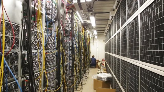 Close-up of data center of the large company with lots of fans, system units and wires and young network administrator pluging in wires. Stock footage. IT professionals concept