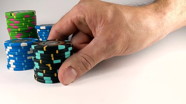 Male hand moving a black stack of poker chips across the white table, ISOLATED, SLOMO, STILL
