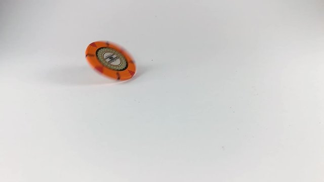 An orange poker chip spinning on a white table, STILL, ISOLATED