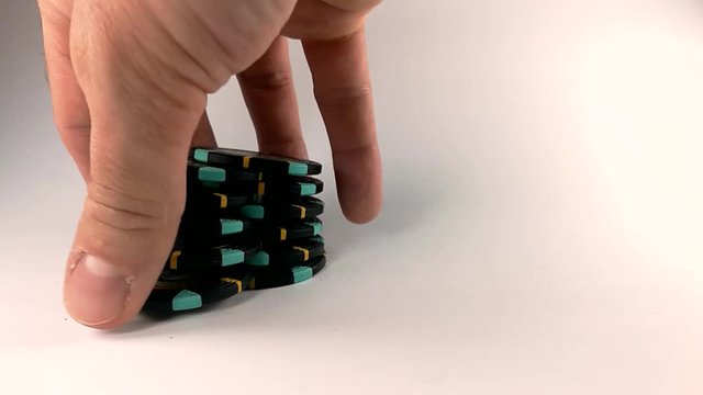 Male hand shuffling black poker chips on a white table, STILL, ISOLATED