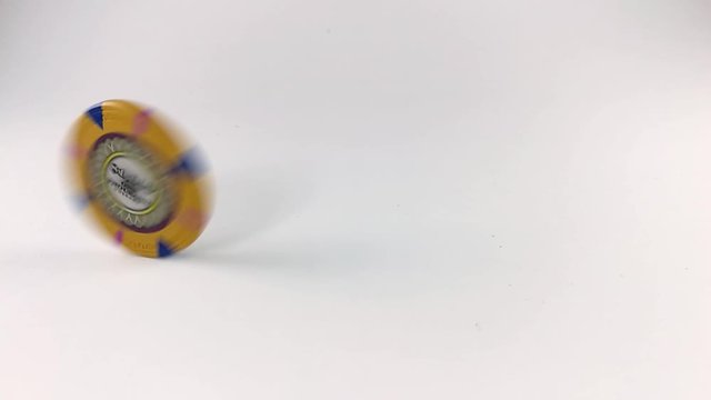 Yellow poker chip spinning on a white table, ISOLATED, STILL, SLOMO