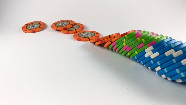 Stack of colorful poker chips falling down from right side on a white table, ISOLATED, STILL, SLOMO