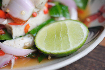 Close of lemon in spicy salad with steamed pork sausage