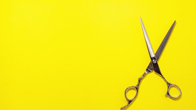 Stop motion animation flat lay of professional hair cutting shears on the right side on yellow background. Hairdresser salon equipment concept, premium set