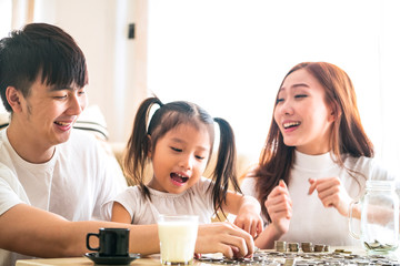 young father and mother teaching their kids to  saving money to piggy glass bank