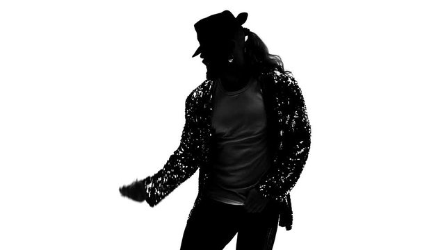 Silhouette of a young man dancer dancing in style Michael Jackson on white background. Close up, slow motion.