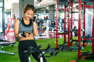 Fototapeta na wymiar Yong beautiful woman listening musing during workout at gym