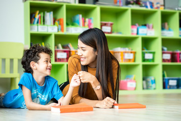 kindergarten student knock bump together with his teacher after finished doing his homework report at kindergarten school
