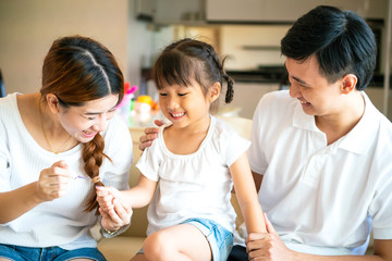 portrait of asian mother painting her daughter nail in living room, family concept