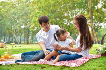 Naklejka na ściany i meble portrait of happy Asian family with picnic meal in relaxing day in garden, Asian family concept