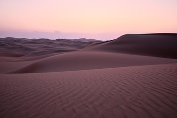 Abstract view of sand dunes in the desert with pick glowing light after sunset. Liwa desert, Empty Quarter, United Arab Emirates.