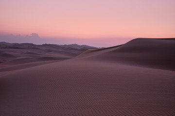 Abstract view of sand dunes in the desert with pick glowing light after sunset. Liwa desert, Empty Quarter, United Arab Emirates.