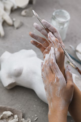 Hands of a girl sculptor in plaster with a brush