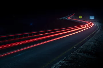 Foto op Plexiglas snelweg lange blootstelling voertuig licht paden bochtige snelweg tussen bergen eilat israël © Thomas
