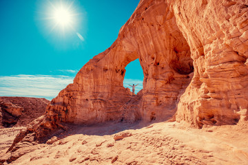 Arch in the rock. A human with hands in the air stays in the arch. Desert natural landscape. Timna Park. Israel