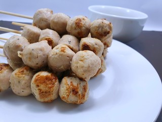 Selective focus of grilled pork balls skewers on white plate, Ready to eat or serve (tubular fish paste, fish stick)