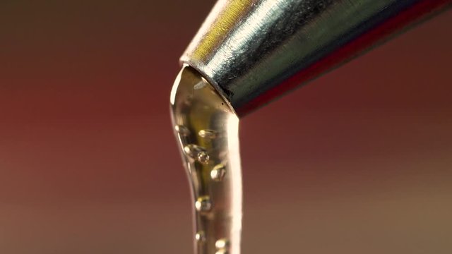 Macro extreme close up hot glue dripping out from metal nozzle