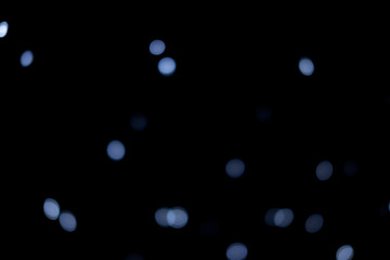 Silver and blue lights of the festive city on black background.