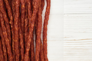 long and thin sausages kabanos on white wooden background, isolated