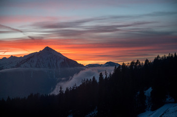 colorful winter sunset with Mount Niesen, clouds and forest