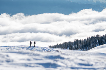Naklejka na ściany i meble couple of snowshoe hikers in front of a sea of fog