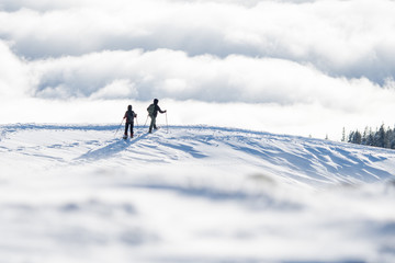 Fototapeta na wymiar couple of snowshoe hikers in front of a sea of fog