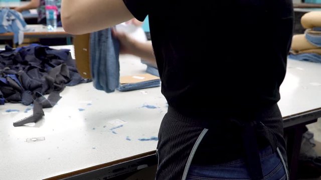 Manufacture of clothes at a garment factory. The worker of the sewing factory collects parts of fabric cut by the automatic laser machine into sets. 4k footage.