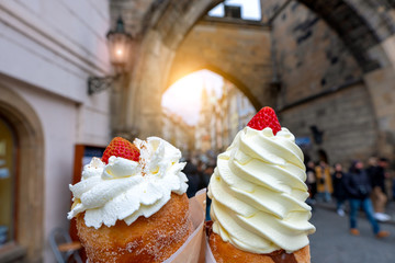 Prague trdelnik with cream and strawberries on the background of Prague