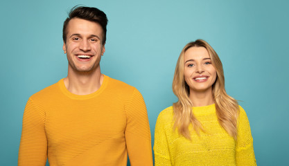 We are who we are. Close-up photo of a lovely couple, who are posing in yellow sweaters, both looking in the camera and smiling.