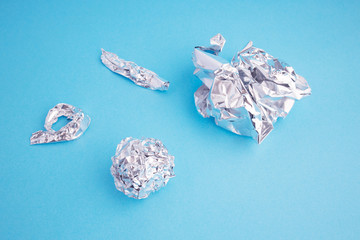Aluminium foil on blue background. Metal parts of crumpled foil.