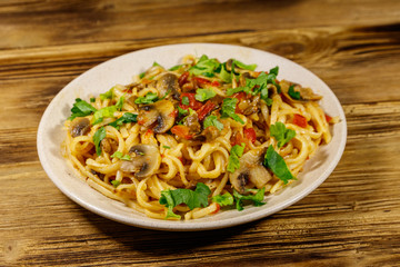 Pasta with mushrooms and tomato sauce on wooden table