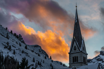 Church steeple with snowy mountain and clouds at sunset