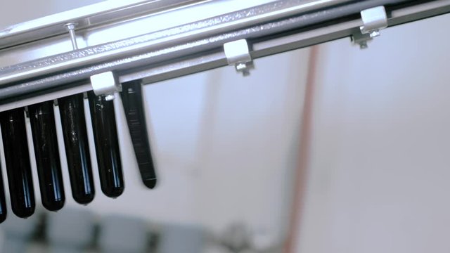 A row of dark plastic preforms of PET bottles. Production process