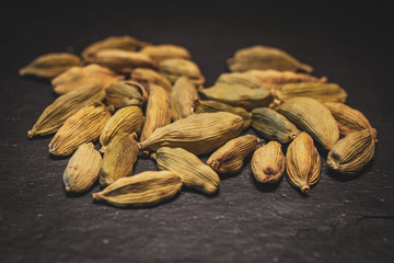 Macro view of green cardamom seeds on slate background. Spices of the world. 
