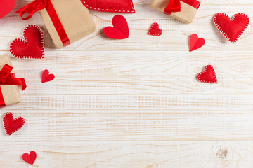 Preparation for Valentine's Day. Red hearts and craft gifts on white wooden background. Copy space.