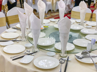 White elegant banquet table setup with glasses and ceramic tableware 