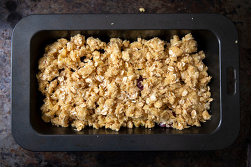 Preparation for fresh plum crumble in the oven dish