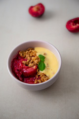 Fresh bright red plum crumble in the pink bowl