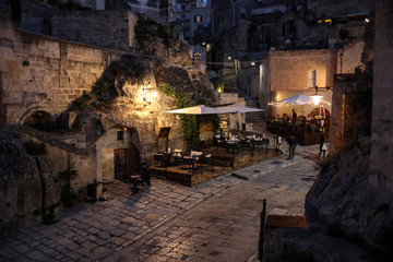  Evening view of the city of Matera, Italy, with the colorful lights highlighting patios of sidewalk cafes in the Sassi di Matera a historic district in the city of Matera. Basilicata. Italy