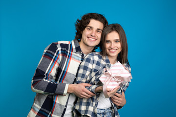 Front view of happy couple with gift isolated on blue background