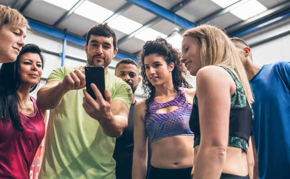 Group of athletes looking at the mobile of a gym mate