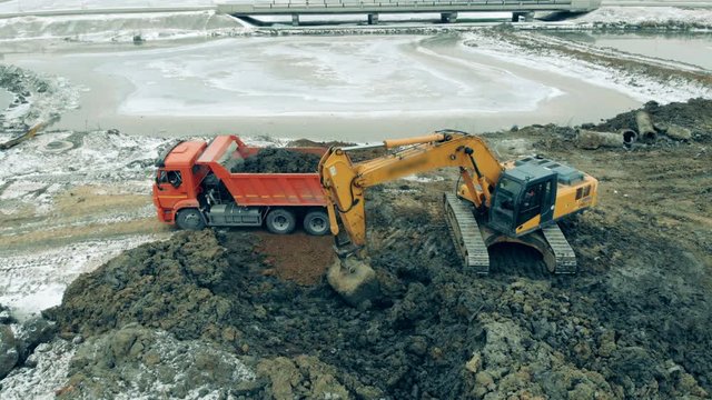 Industrial tractor loads a truck with sand at a quarry. New constructions site. Heavy machinery at a construction site.