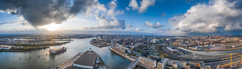 Obraz premium Aerial drone panoramic view of port of Hamburg from above before sunset with dramatic stormy clouds over the sea port