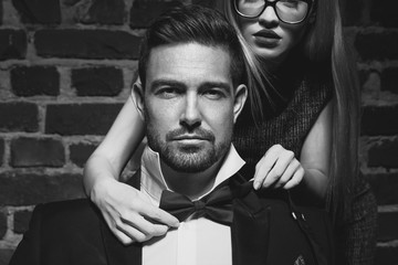 Woman tie bow for sexy man in tuxedo black and white
