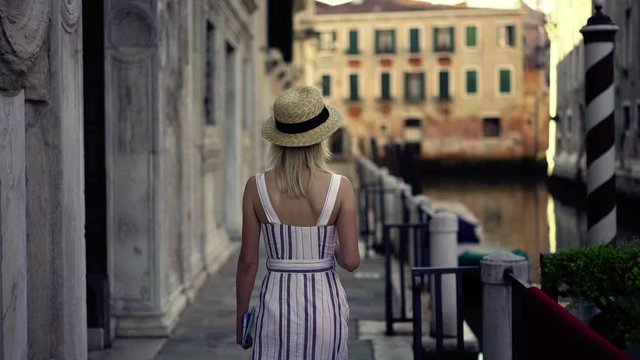 Young beautiful woman tourist dressed in stylish apparel walking around italian romantic street near water canal enjoying leisure time for wanderlust, concept of travelling and sightseeing