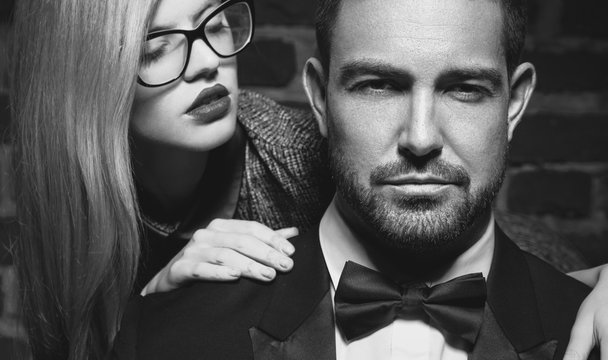 Sensual young woman seducing sexy macho man in tuxedo