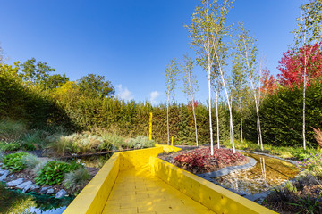Garden design with colorful yellow stone pathway and pond